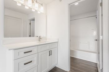 A white bathroom with a large mirror and a sink and a shower